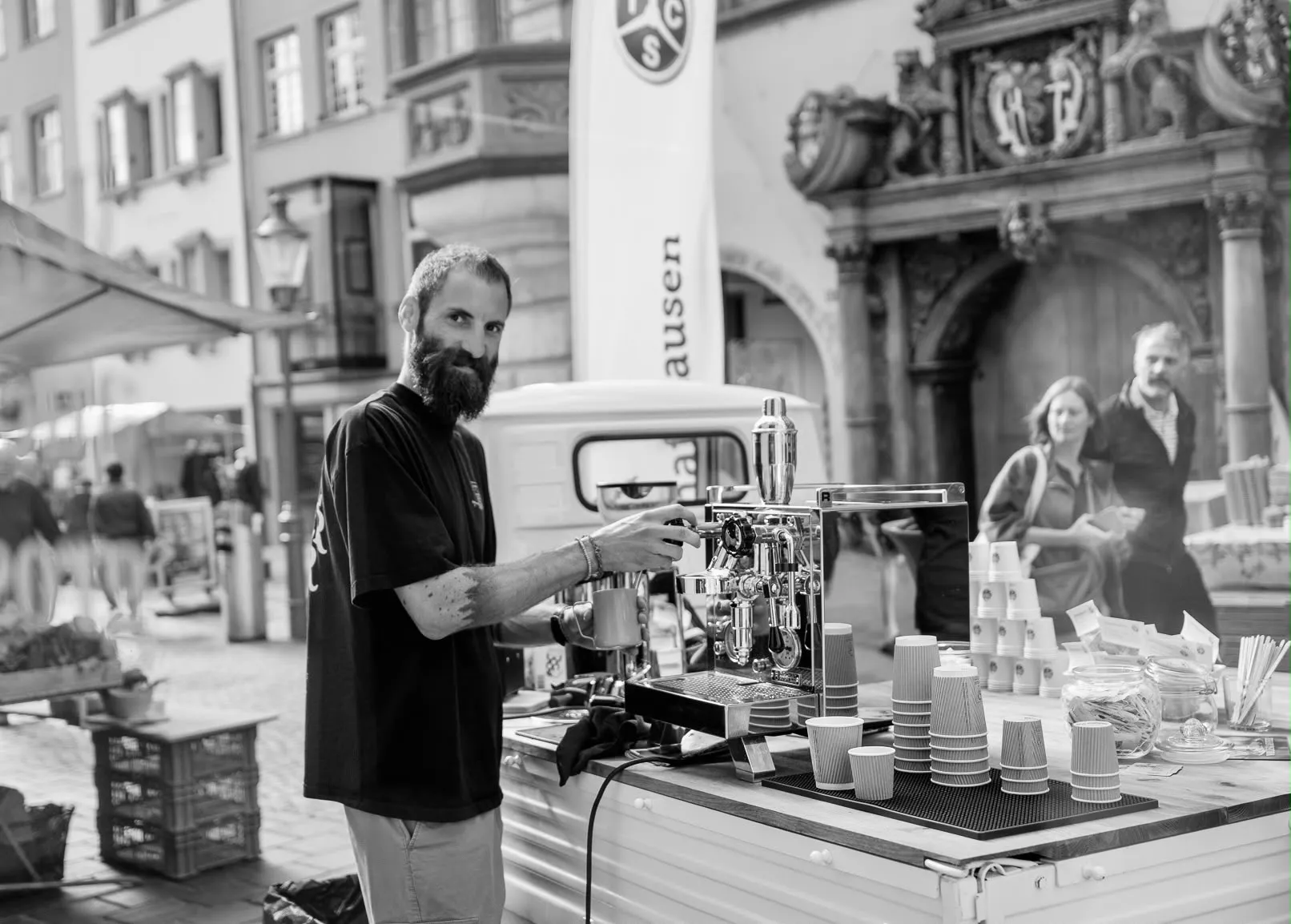 Kim bereitet an der Siebträgermaschine Kaffee zu, mobiler Barista-Stand in der Schaffhauser Altstadt, Schwarzweiss-Aufnahme