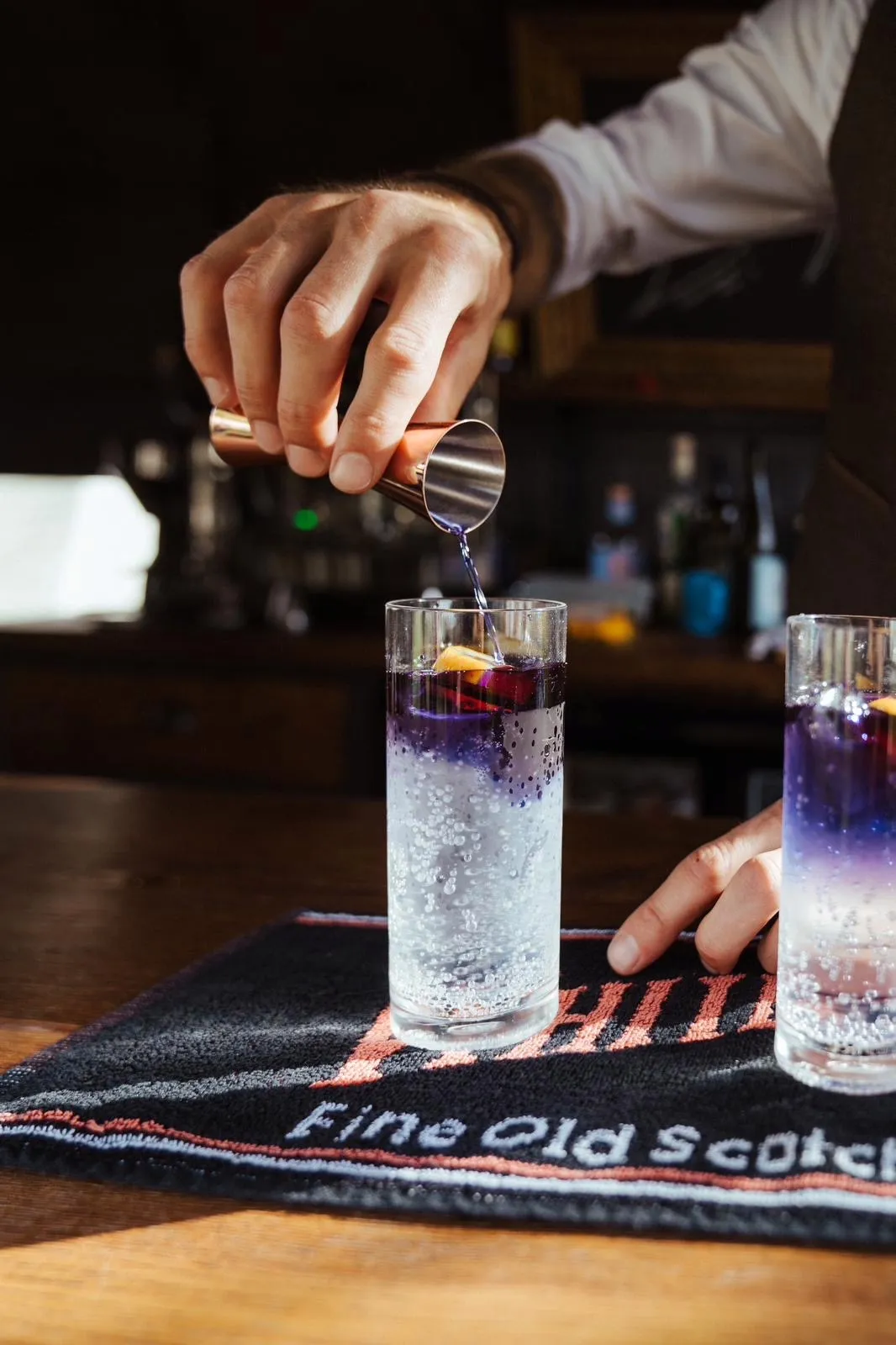 Barkeeper giesst eine Spirituose auf einen Gin Tonic, Nahaufnahme
